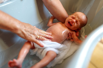 Mother bath crying newborn baby at home