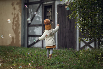 girl playing with soap bubbles outdoors