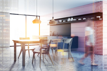 Woman in pink tile kitchen interior, table