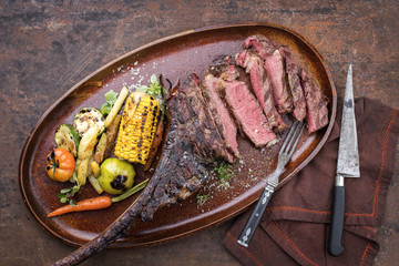Traditional barbecue dry aged sliced wagyu tomahawk steak with grilled vegetable as top view on a plate