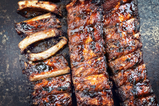 Barbecue spare ribs St Louis cut with hot honey chili marinade as top view on old rusty board