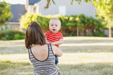 Group portrait of Caucasian mother with baby boy in red t-shirt in field meadow outside. Female...