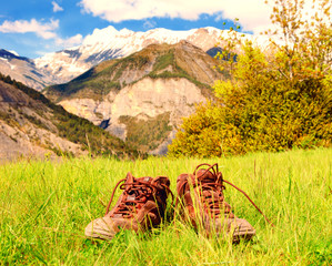 Old hiking shoes and Alpine landscape at background. Provence-Alpes-Cote d'Azur region of France. Summer wandering. 