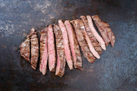 Barbecue dry aged wagyu flank steak sliced as top view on an old metal sheet with copy space