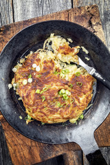 Traditional Swiss hash browns as side dish with leek as closeup in a frying pan