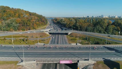 Aerial drone footage. Fly to marathon running group on the road junction, wide shot