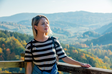 Fototapeta na wymiar Style girl stay on top of building and relax. Forest and mountains on background. Autumn season time scene