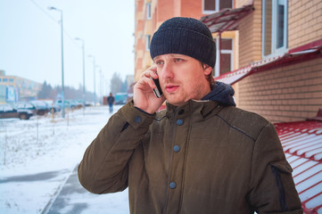 Man in winter city speaks by phone.