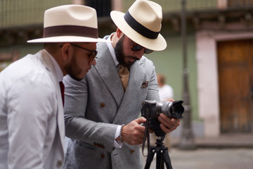 Two stylish men setting up a video camera