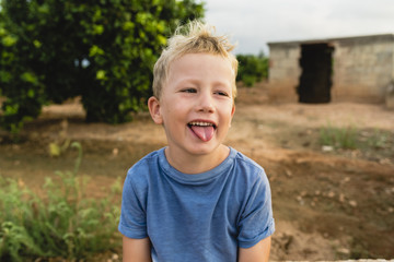 Blond boy making funny faces outdoors