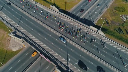 Aerial drone footage. Following marathon running group on the road junction, close up