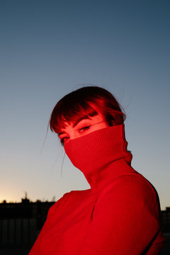 Portrait of young woman in maroon turtleneck covering lower half face