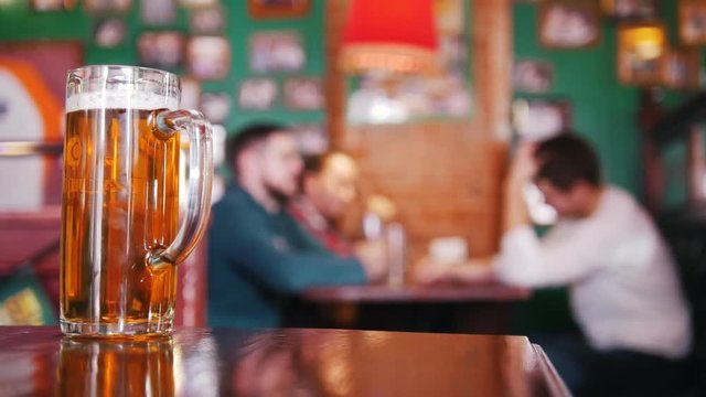 Guy friends drinking beer on the background. Pint of beer in focus