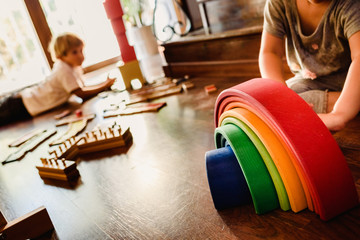 Fototapeta na wymiar Children playing with wooden rainbow waldorf montessori