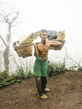 Smoking laborer with baskets of sulfur