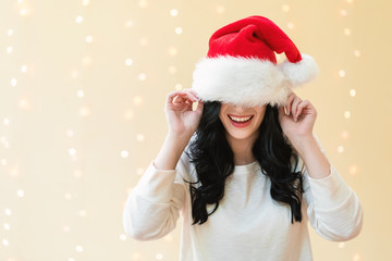 Woman with a Santa hat pulled over her eyes on a shiny light background