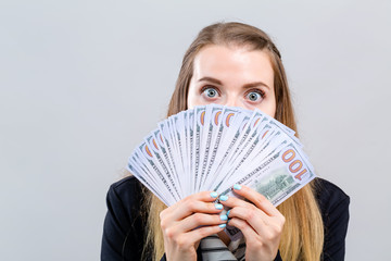 Young woman with a stack of cash USD on a gray background