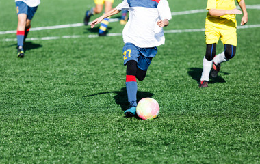 Obraz premium football teams - boys in red, blue, white uniform play soccer on the green field. boys dribbling. dribbling skills. Team game, training, active lifestyle, hobby, sport for kids concept