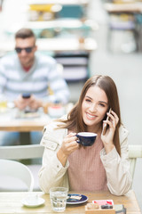 Young beautiful woman in a cafe talking on a phone and smiling