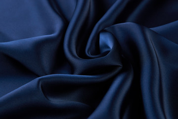 Dark blue silk fabric background, view from above. Smooth elegant blue silk or satin luxury cloth...