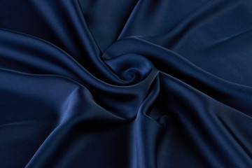 Dark blue silk fabric background, view from above. Smooth elegant blue silk or satin luxury cloth...