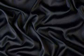 Black silk fabric background, view from above. Smooth elegant black silk or satin luxury cloth texture can use as abstract background with copy space, close-up 
