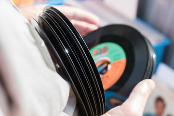Person sucht aus einem Stapel unverpackte  gebrauchte Vinyl Single Schallplatten aus