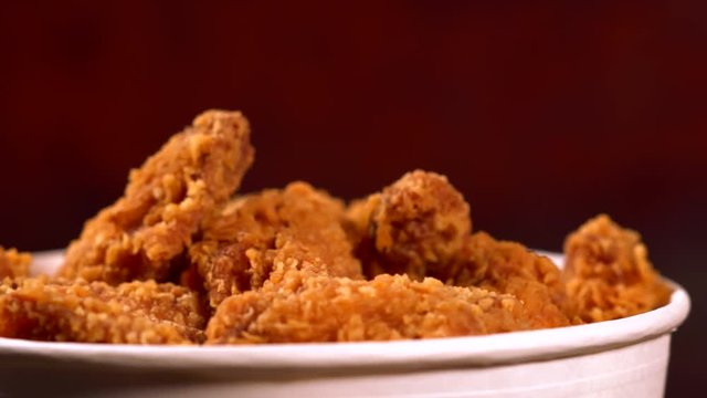 Tub of fried chicken pieces coated in crumbs