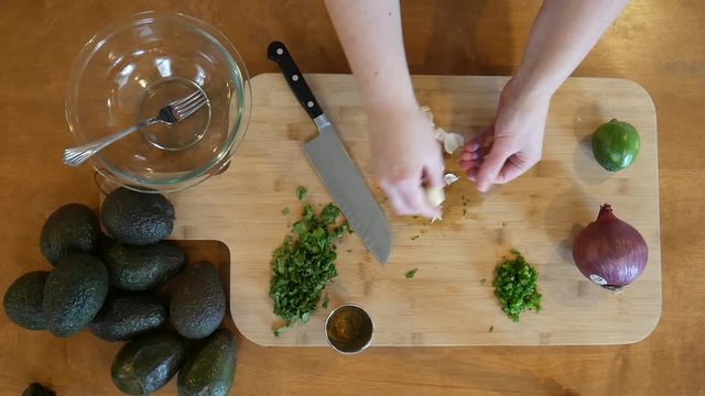 Overhead close up, peeling garlic on cutting board