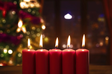Five candles in blurred Christmas tree background