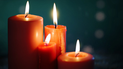 Four candles burning on dark background
