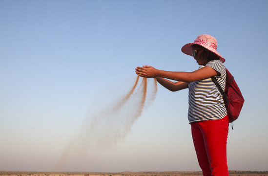Teenage girl making fun with sand in Thar Desert