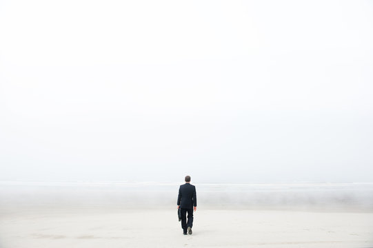 Businessman walking on a foggy beach
