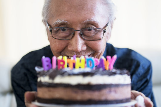 Happy old man holding chocolate birthday cake