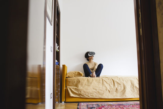 Woman sitting on the bed with virtual reality headset
