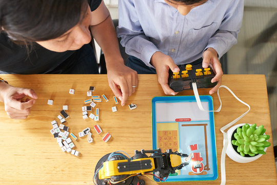 Young boy and woman playing hang man with mechanical robot