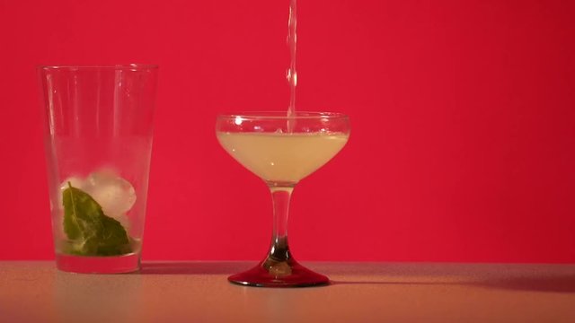 Close up, person pours gimlet into glass