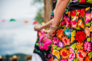 bailarinas con faldas floreadas bordadas a mano, mujeres de oaxaca con pulseras de oro en fiesta de la guelageutza