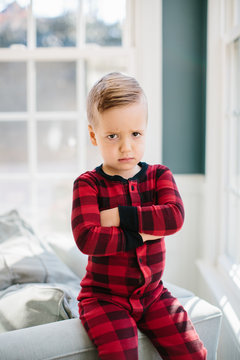 Adorable young boy in a plaid pajamas pouting