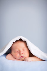 Newborn Baby Boy Sleeping Peacefully Under Blue Blanket, Room for Text