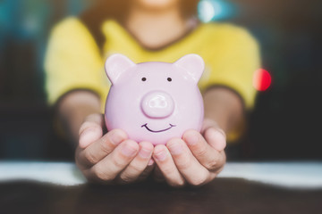 Female hand holding piggy bank. Save money and financial investment