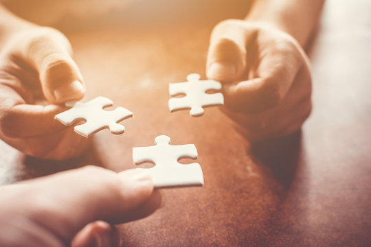 Hand Of Two People Holding Jigsaw Puzzle Connecting Together. Concept Of Partnership And Teamwork In Business Strategy