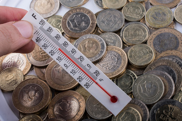 Thermometer in hand beside Turkish Lira coins