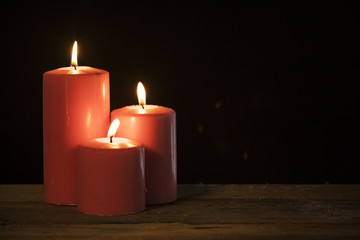 Three candles glowing in dark background