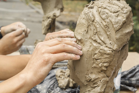 sculptor creates a bust and puts his hands clay on the skeleton of the sculpture. Close-up