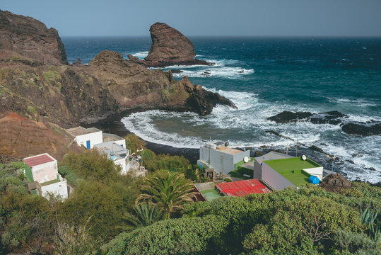 Small coastal fishing village with mountains and rocks in a background