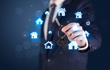Businessman in suit holding keys with house graphics around and dark background
