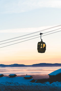 A gondola passing in front of a winter sunset