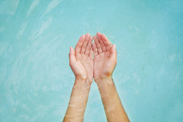 Woman's hands in blue water holding water