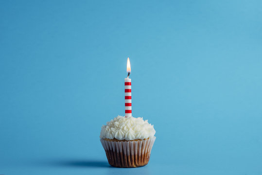 Cupcake with birthday candle on a blue background